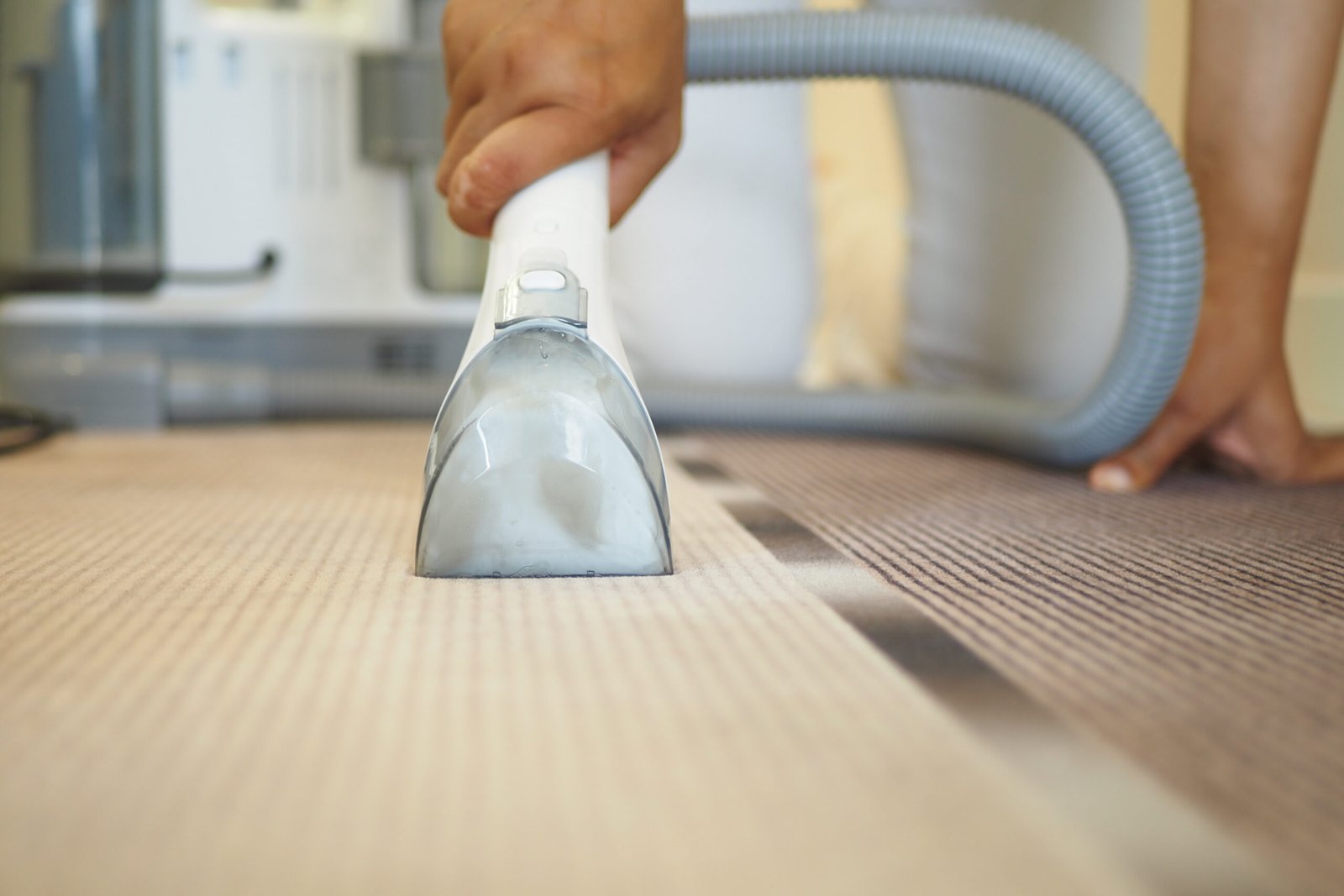 A hand using a vacuum cleaner on a carpet, ensuring cleanliness in a stylish home.