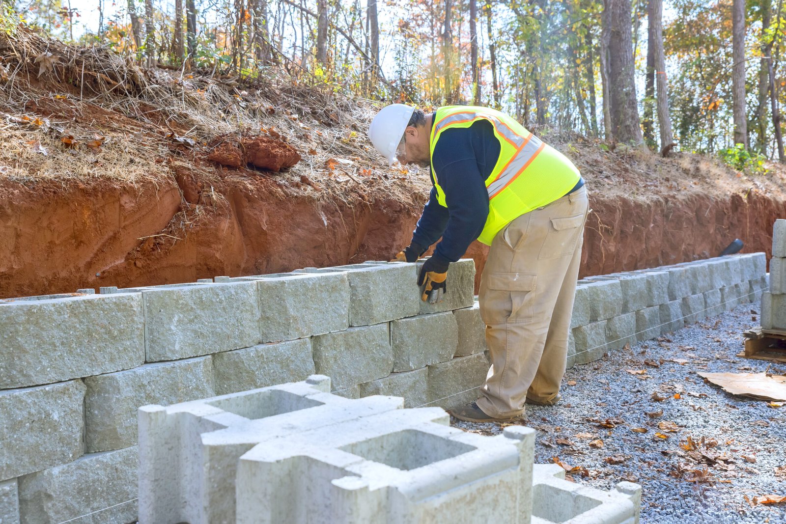 Retaining wall is being constructed using A retaining wall is being constructed using cement blocks by construction worker during development of new property. by construction worker during development of new property.
