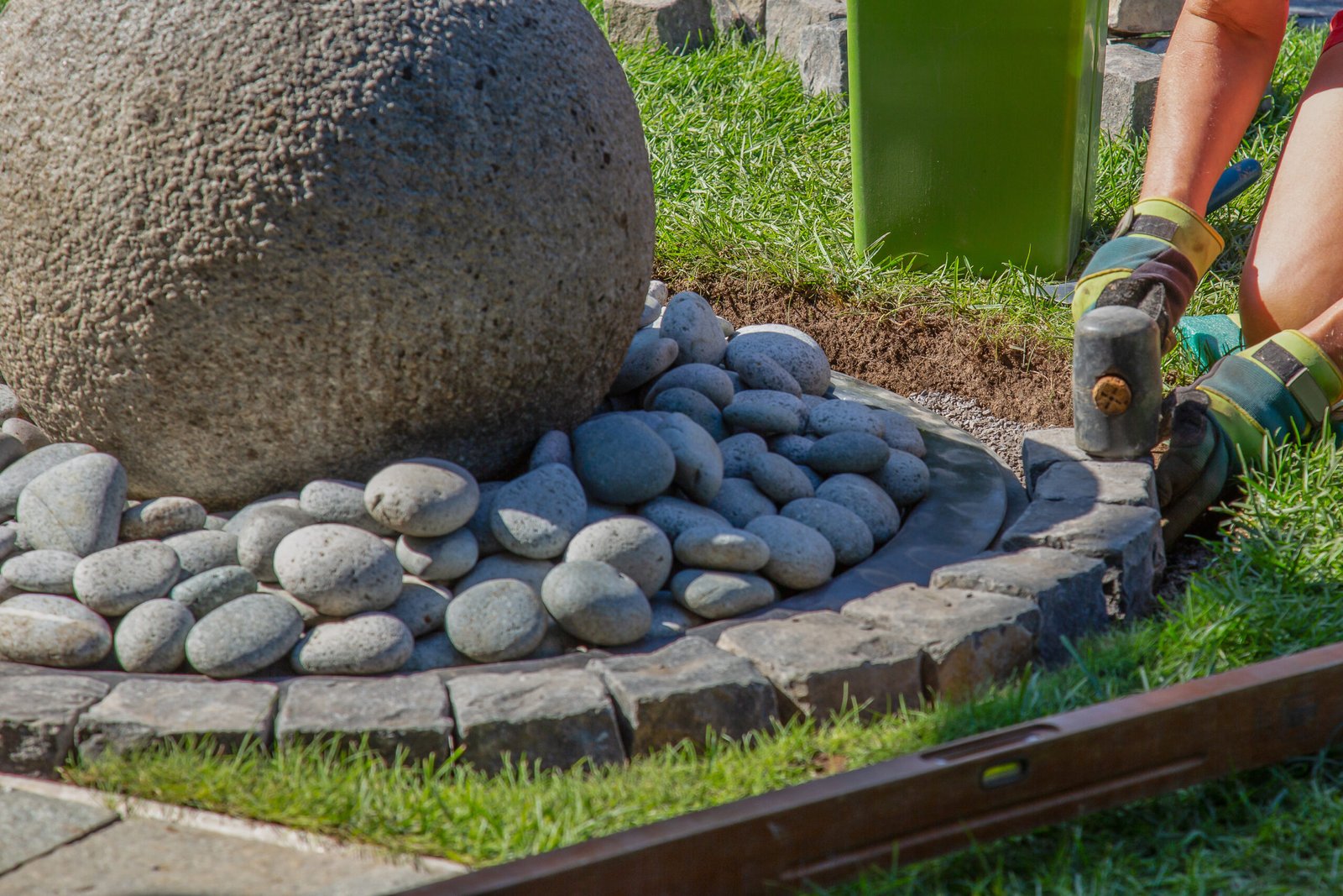 A closeup shot of a handyman laying cobblestones using a mallet