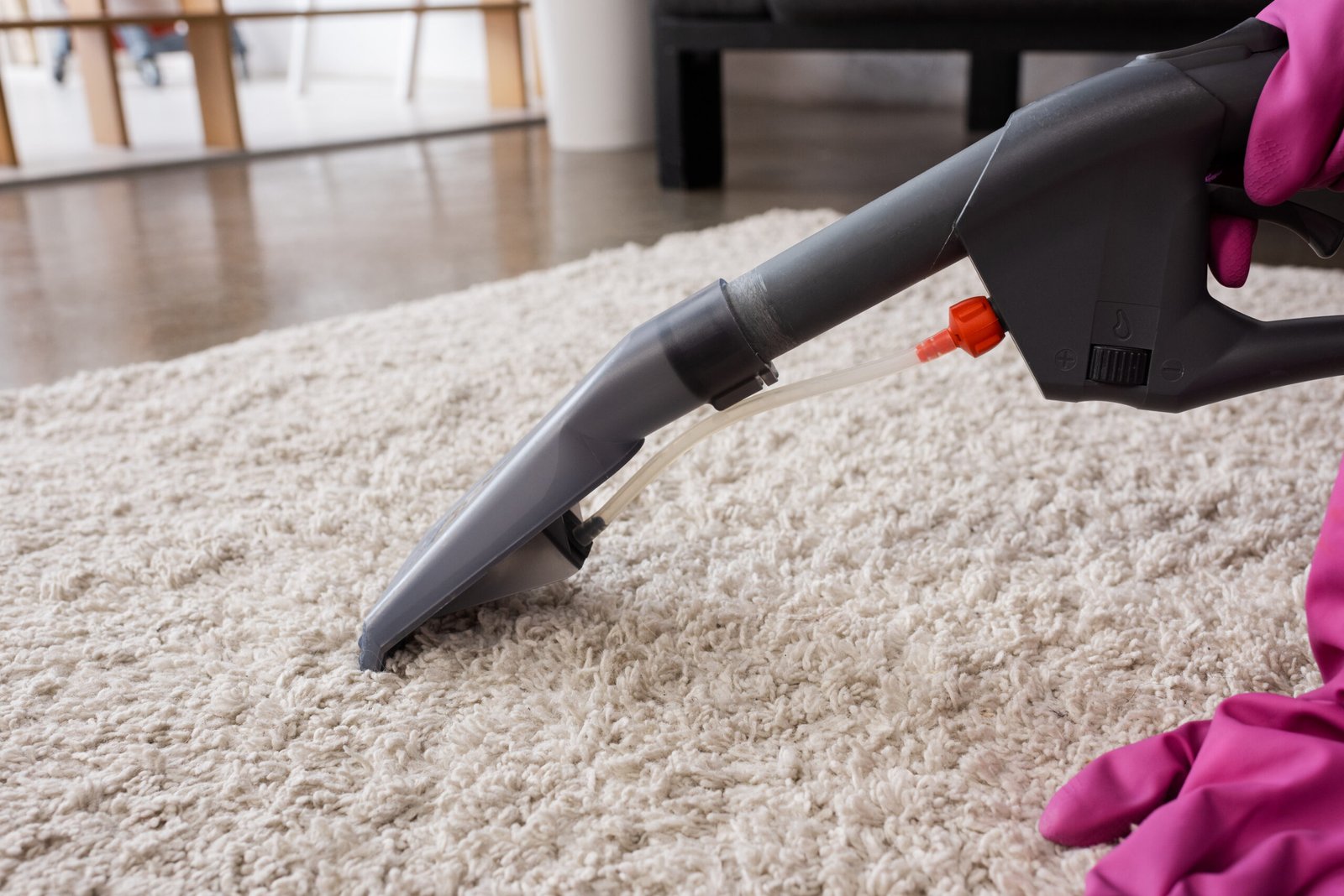 Cropped view of cleaner in rubber gloves cleaning carpet at home