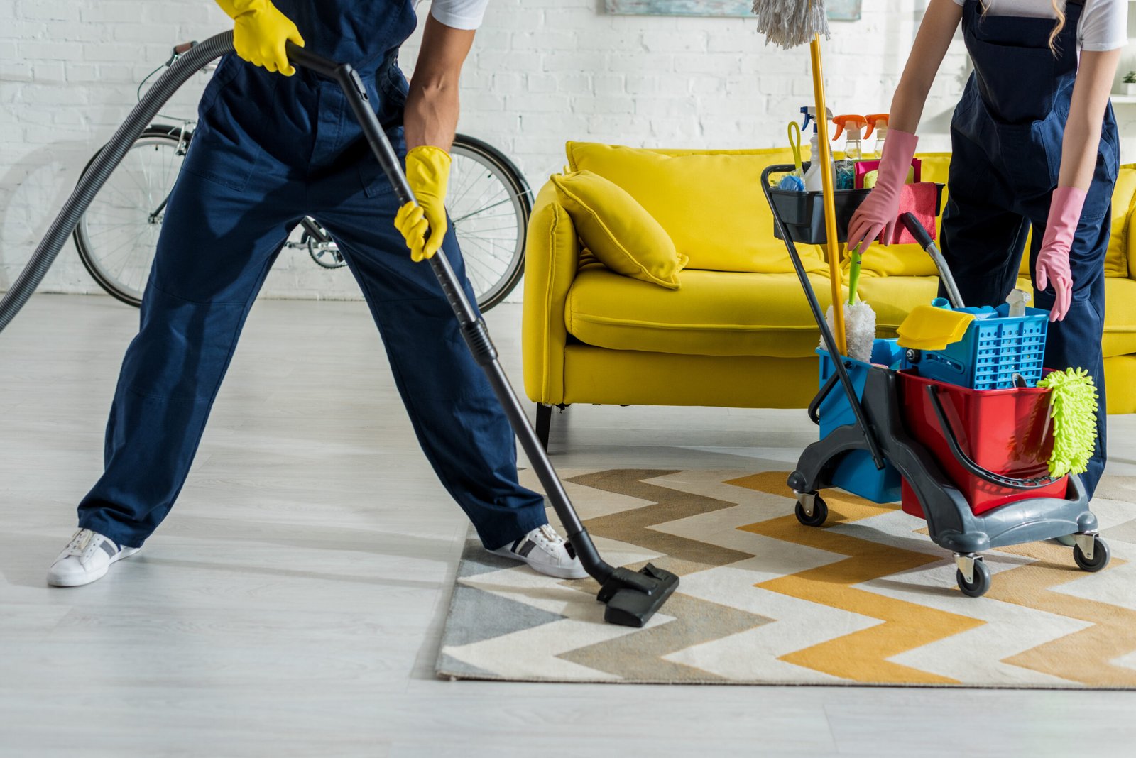 cropped view of cleaners in overalls cleaning apartment