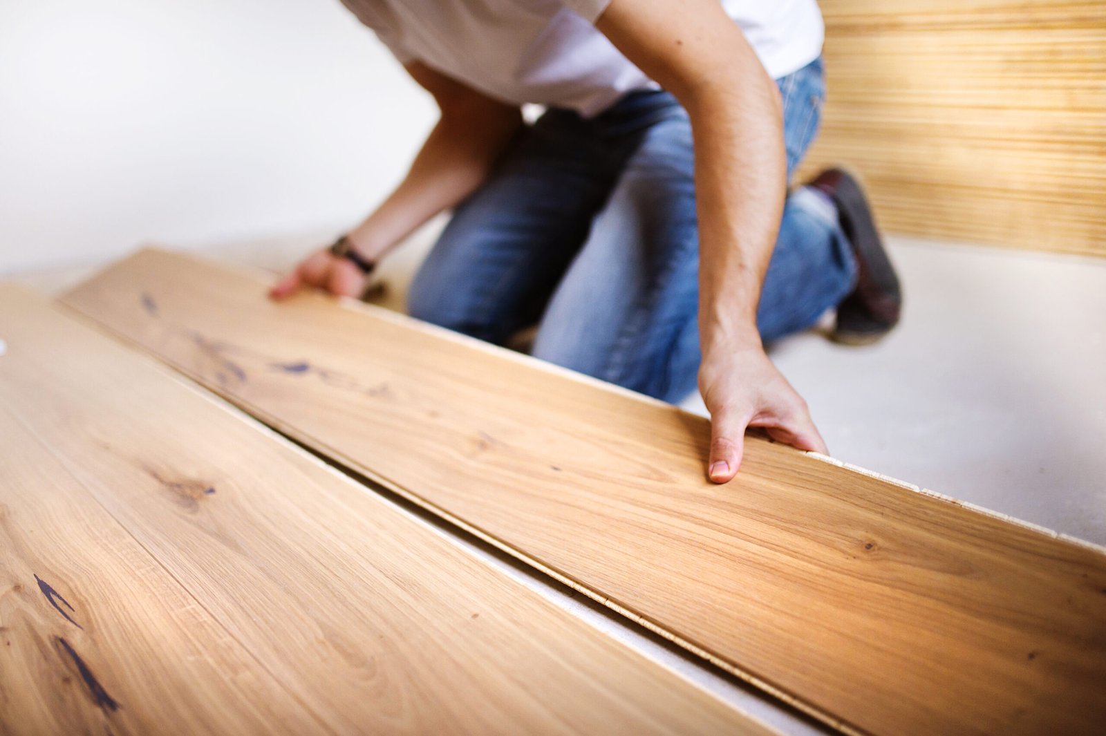 Unrecognizable handyman installing wooden floor in new house