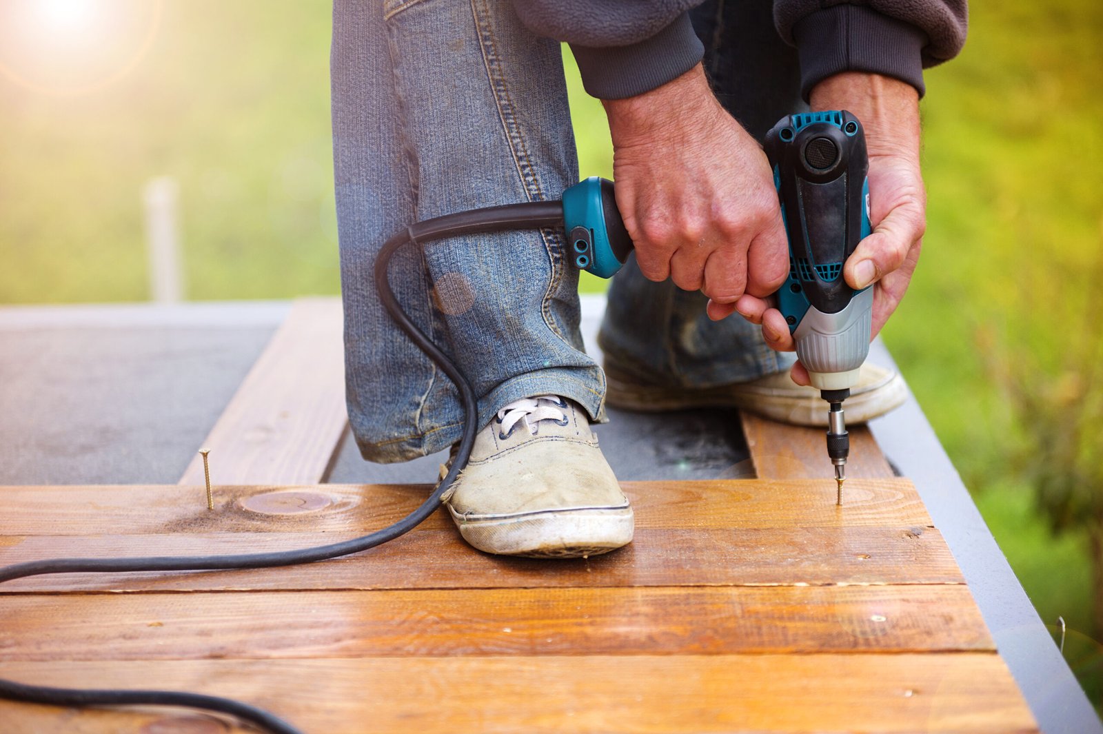 Handymen installing wooden flooring in patio, working with drilling machine