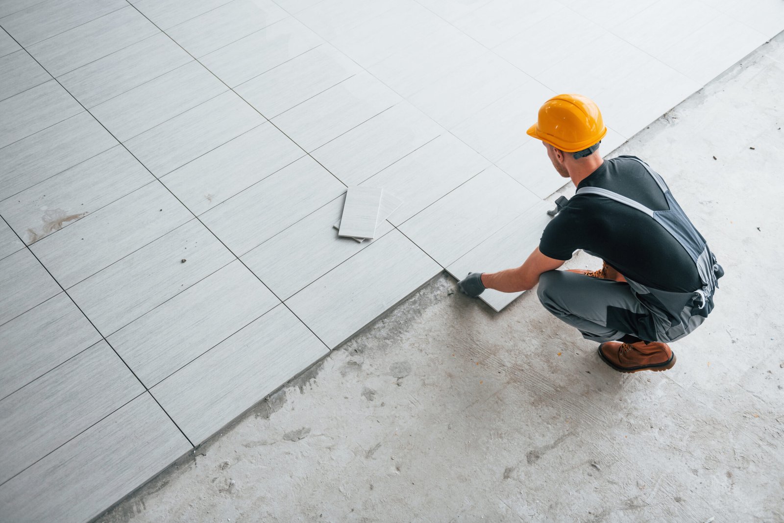 Top view of man in grey uniform that installing plate indoors in modern big office at daytime.