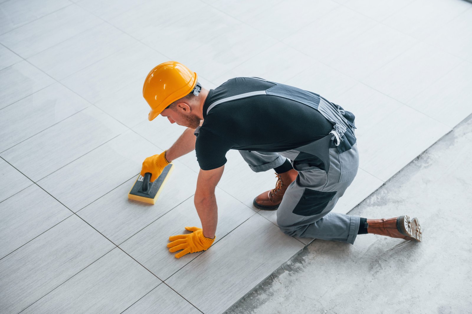 Top view of man in grey uniform that installing plate indoors in modern big office at daytime.