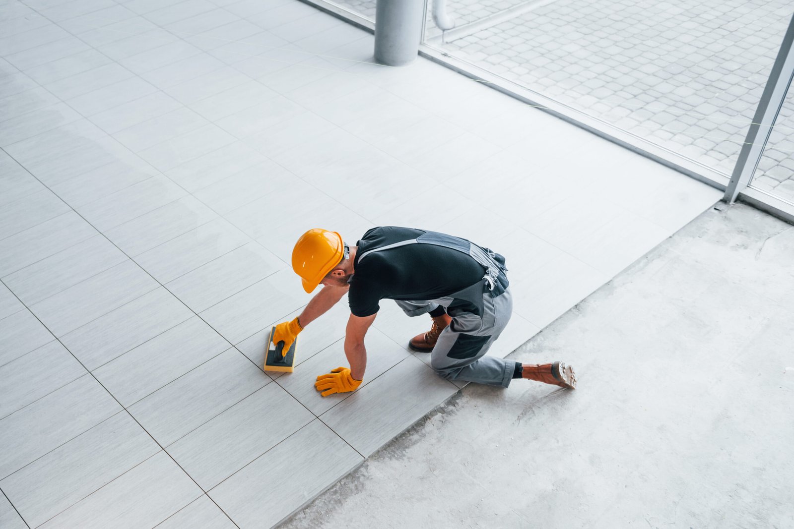 Top view of man in grey uniform that installing plate indoors in modern big office at daytime.